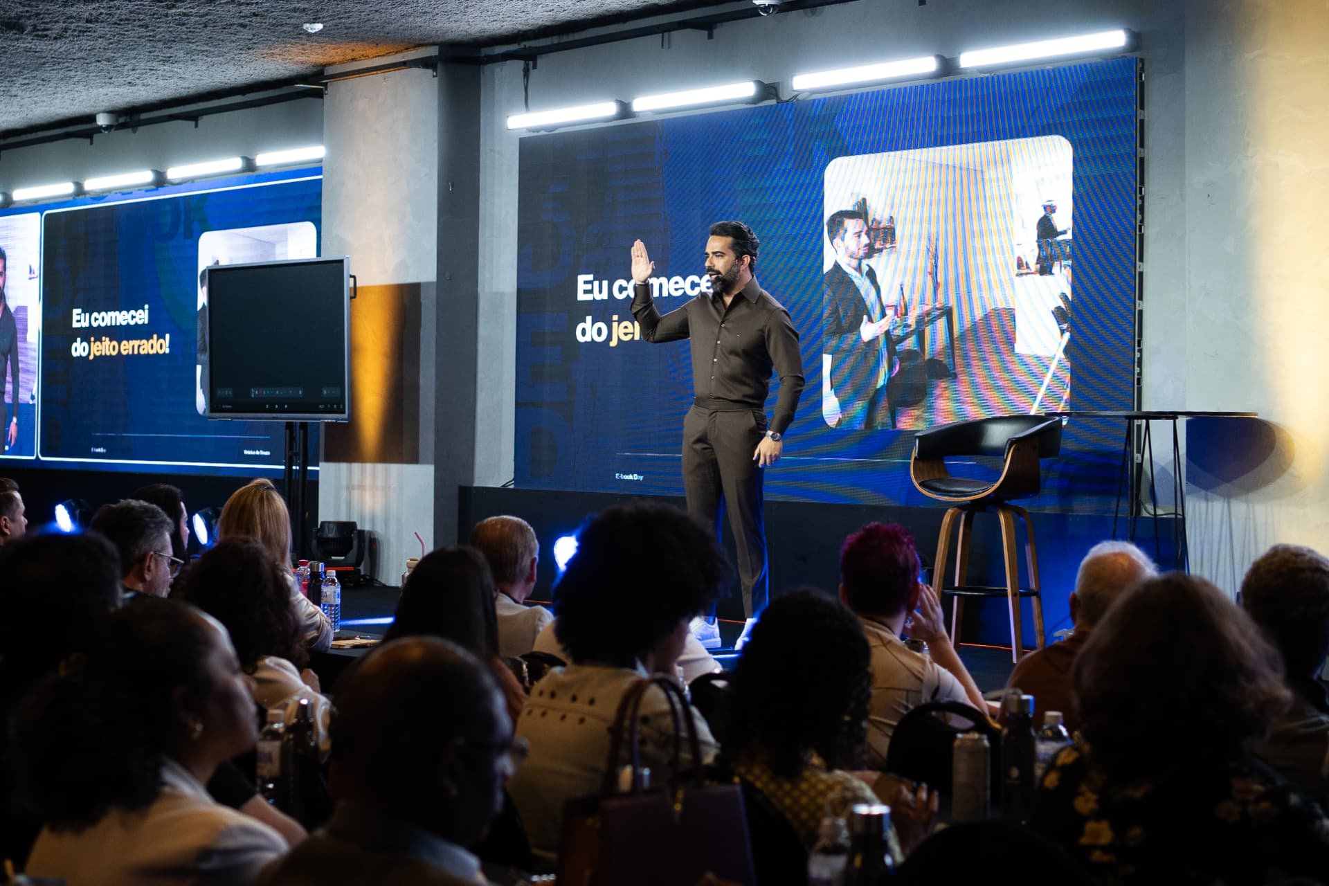 Vinicius Souza no palco durante evento presencial com plateia